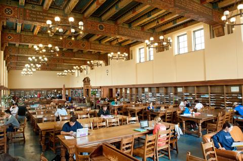 spacious room with tall ornate ceilings and many wooden tables