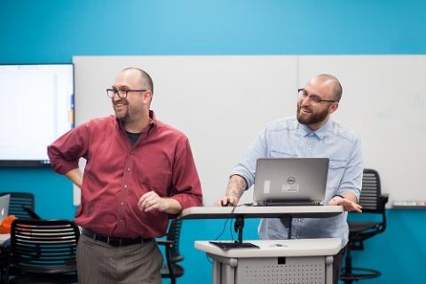 Two instructors in front of a blue-painted wall