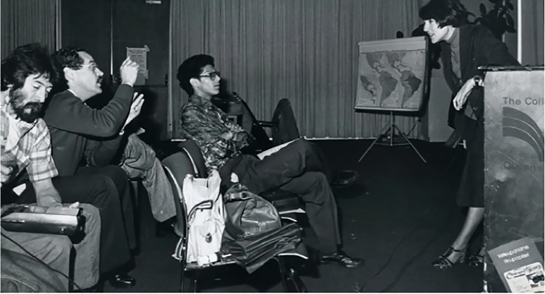 Jacqueline Barnitz, scholar of Latin American art and professor emeritus lecturing to a small group of men.