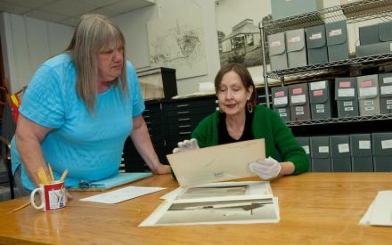 Area is a photo of the Alexander Architectural Archives area.  Two women admire some documents at a table.